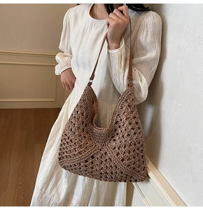 Detail of tan hollow out woven tote bag with adjustable leather strap worn by a model