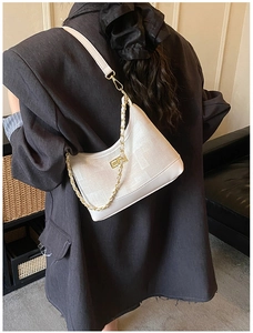 Detailed back view of a white crescent shoulder bag with gold chain and metal clasp