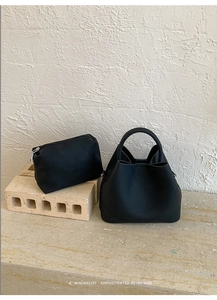 Close-up of black lychee leather bucket bag with matching pouch and ring handle detail