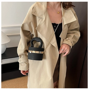 Dettaglio di borsa da sera cilindrica in acrilico nero con catena d'oro e manico a U