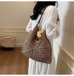 Detailed side view of a brown woven straw tote bag with leather shoulder strap