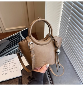 Détail du sac seau marron café avec poignée circulaire et pendentif en forme de cœur