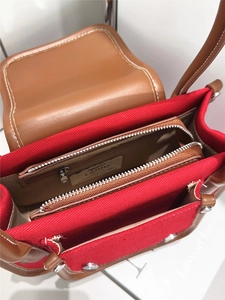 Détail de l'intérieur du sac en cuir marron avec doublure rouge et poches zippées