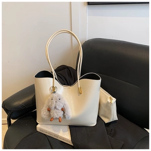 Détail d'un sac cabas beige en cuir avec pochette assortie et pendentif lapin gris