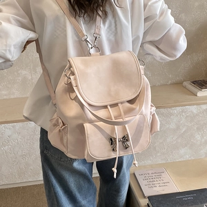 Détail d'un sac à dos rose minimaliste avec un nœud argenté et des poches latérales