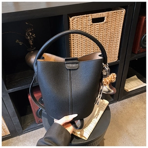 Détail du sac seau noir en cuir grainé avec pompon léopard et pendentif métallique doré