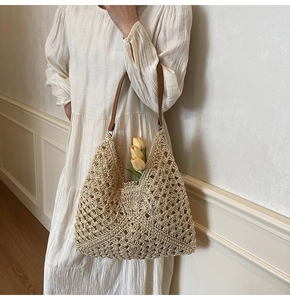 Detail of hollow woven tote bag with brown leather straps and tulip flowers inside