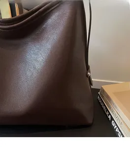 Gros plan sur la texture du cuir marron et la boucle métallique argentée du sac à main