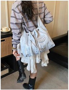 Detailed view of punk style light blue bucket bag with decorative studs and motor zippers