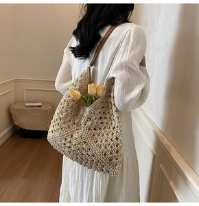 Close-up of beige crochet woven tote bag with brown leather strap and floral detail