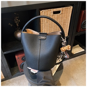 Détail du sac seau en cuir noir grainé avec pendentif nœud léopard et bandoulière réglable