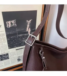 Détail d'un sac à main en cuir marron foncé avec boucle métallique carrée argentée réglable