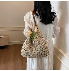 Detailed texture of beige crochet woven tote bag with a brown leather shoulder strap