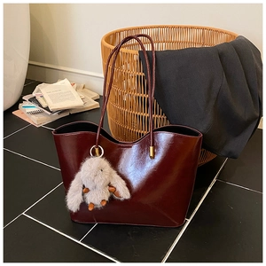 Détail du sac cabas bordeaux en cuir ciré avec pendentif lapin en peluche élégant