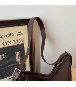 Détail de la bandoulière large en cuir marron avec boucle argentée et fermeture éclair