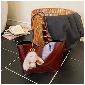 Détail du cabas en cuir verni bordeaux avec un charme lapin gris et un anneau doré