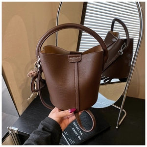 Détail du sac seau en cuir marron avec breloque cœur léopard et bandoulière réglable