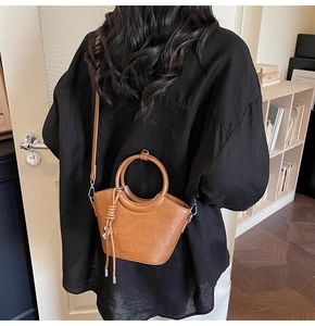 Sac seau caramel avec poignée circulaire et fine bandoulière en ambiance urbaine