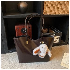 Détail du sac cabas marron foncé brillant avec un joli pendentif de lapin en peluche