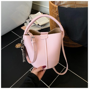 Sac seau rose à texture litchi avec pompon léopard dans un décor d'intérieur