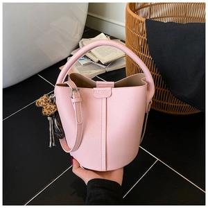 Détail du sac seau rose avec texture grainée et charmant pompon en fourrure léopard