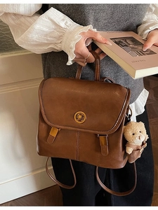 Vintage brown leather backpack with gold buckle and bear charm for school or travel