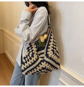 Detail of hand-woven crochet tote bag showing blue and white geometric patterns on shoulder