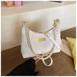 Detail view of white canvas crescent bag with golden chain and metallic twist lock closure