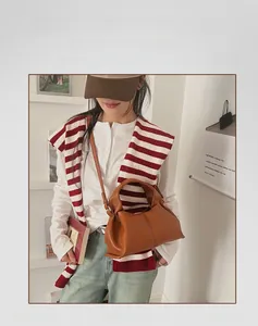 Close-up of brown leather dumpling bag with soft pleats and long shoulder strap