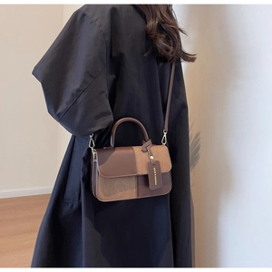 Detail of color-block leather crossbody bag showing metallic gold hardware and stitching