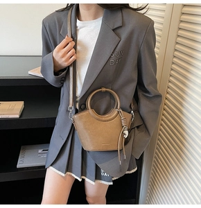 Sac seau marron chic avec texte NO FILTER porté avec un tailleur gris très élégant