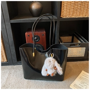 Détail du grand sac cabas noir brillant avec un pendentif lapin en peluche grise