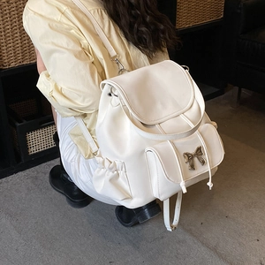 Vue détaillée du sac à dos en similicuir blanc avec une boucle nœud en métal doré