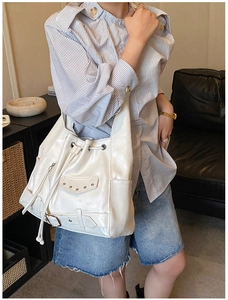 Close-up of white motorcycle bucket bag featuring metallic rivets and drawstring closure