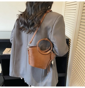 Détail du sac seau marron caramel avec poignée anneau dorée et glands en cuir sur le côté