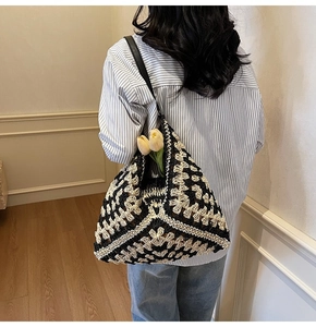 Detail of hand-woven crochet tote bag with black and white geometric pattern and leather strap