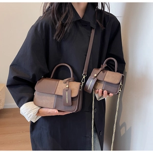 Detail showing two-piece brown color-block crossbody bag set with leather and chain straps