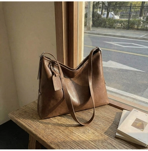 Grand sac fourre-tout en cuir marron vintage avec bandoulière sur un banc en bois