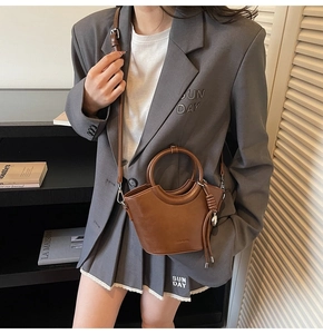 Détail d'un sac seau marron rétro avec poignée en anneau et nœud en cuir tressé