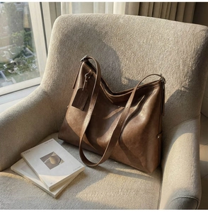 Détail du sac à bandoulière en cuir marron texturé posé sur un canapé élégant