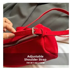 Detail showing adjustable shoulder strap with silver metal buckle on red suede bag