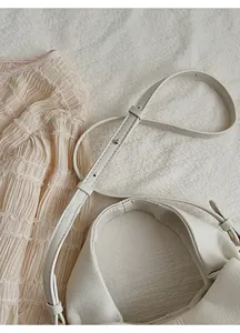 Close-up of white lychee pattern leather shoulder bag with adjustable metal rivet strap