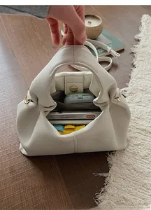 Detail view of white cloud handbag interior with compartments for phone and umbrella