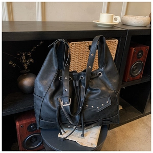 Close-up of retro black biker style bucket bag with metal rivets and drawstring detail