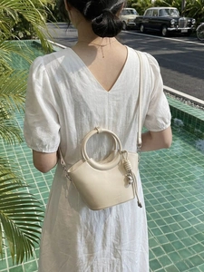Sac seau crème élégant avec poignée ronde et bandoulière dans un cadre de vacances d'été