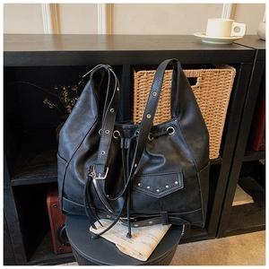 Close-up of black punk hobo bag with silver rivets and metallic buckle details
