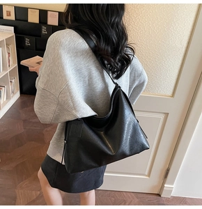 Vue latérale d'un grand sac cabas en cuir noir porté par un mannequin en intérieur