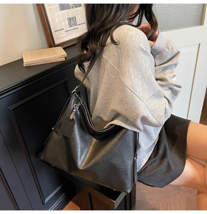 Vue latérale d'un grand sac cabas en cuir noir porté par un mannequin dans une pièce