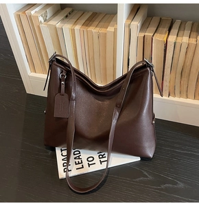 Vue détaillée du grand sac cabas marron foncé avec large bandoulière sur bureau en bois