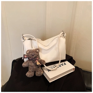 Detail of white litchi pattern leather pillow bag with cute plush bear charm decoration